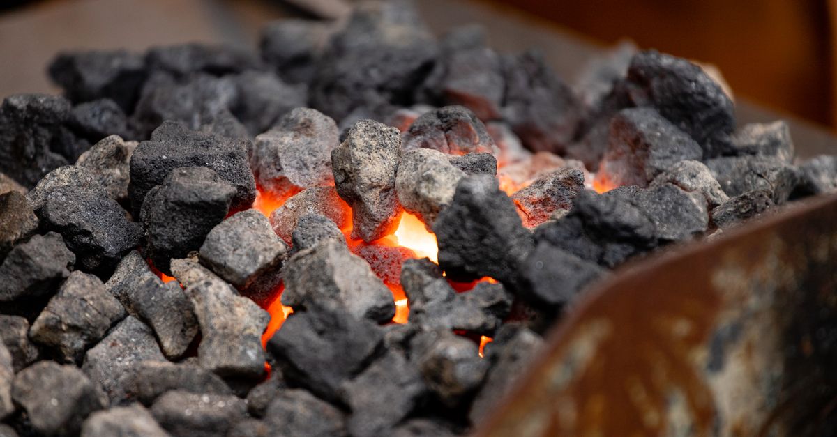 Intense close-up of glowing charcoal, radiating heat and vivid orange hues.